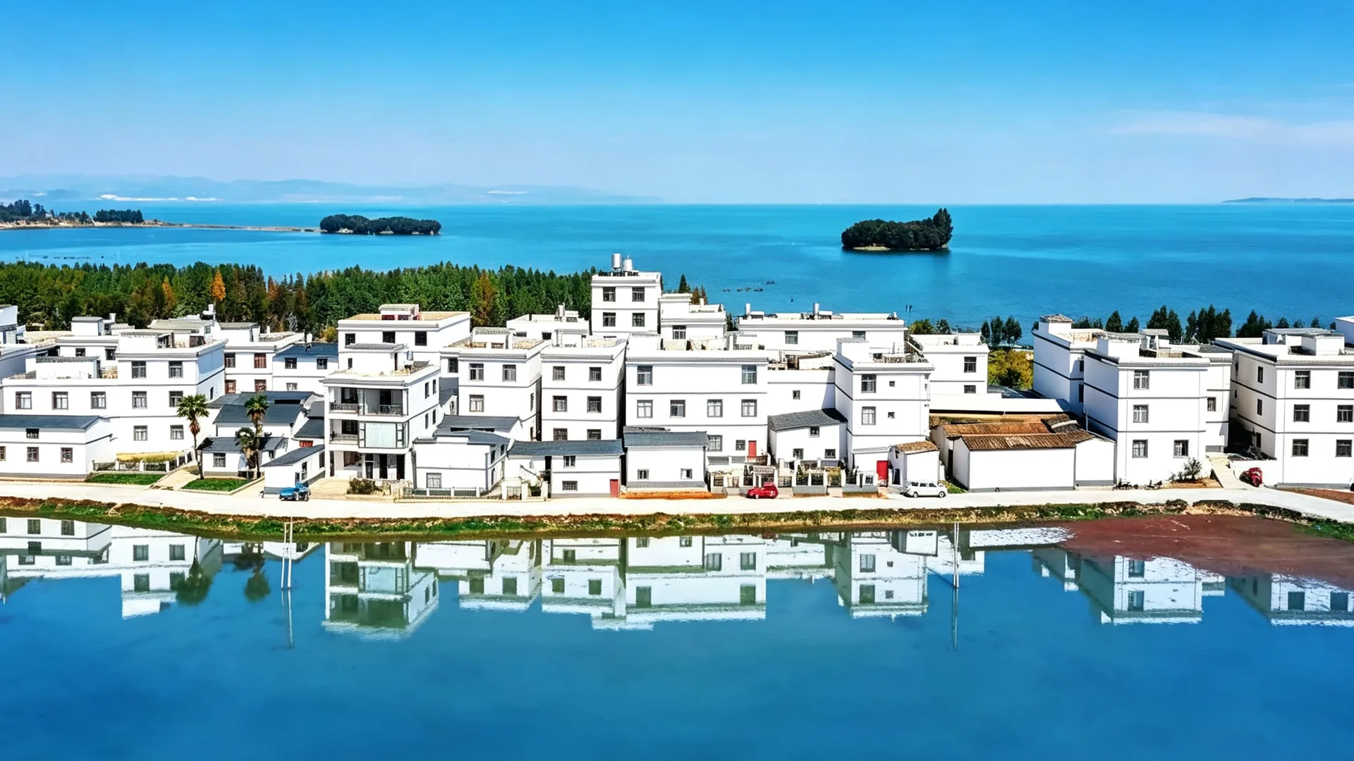 海晏村 — 白色民居倒映在蓝色滇池水面，远处是鲸鱼岛