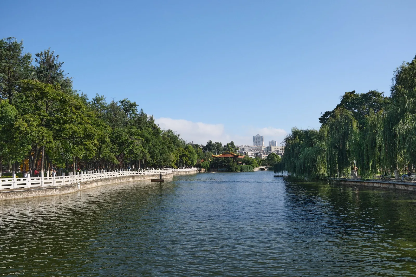 翠湖湖岸全景，白栏杆与柳堤延伸至远处橙瓦亭